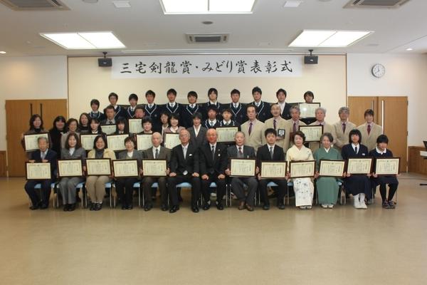 賞を受賞された人達の中で個人と団体の代表者が額に入った賞状を手に持ち前列真ん中に座った市長を囲んで記念写真